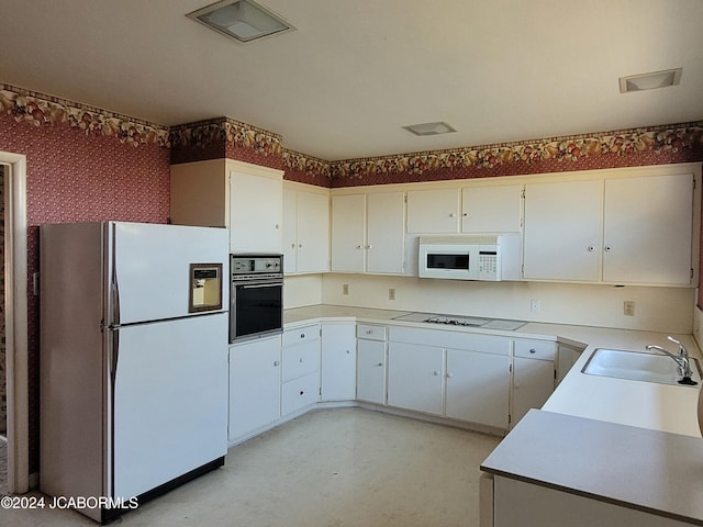 kitchen featuring sink, white cabinets, and white appliances