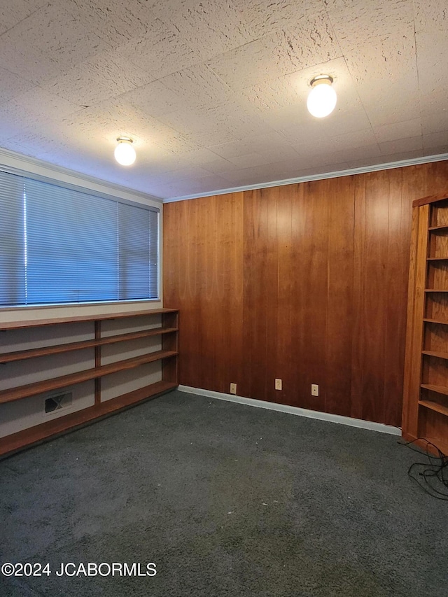 unfurnished room with dark colored carpet and wooden walls