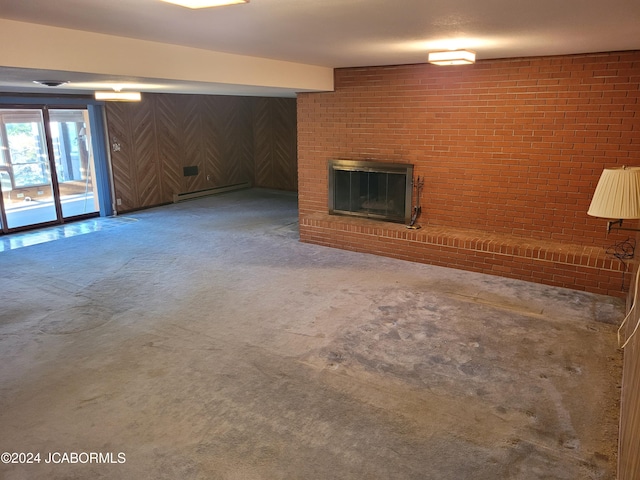 basement featuring carpet flooring, baseboard heating, brick wall, wooden walls, and a fireplace