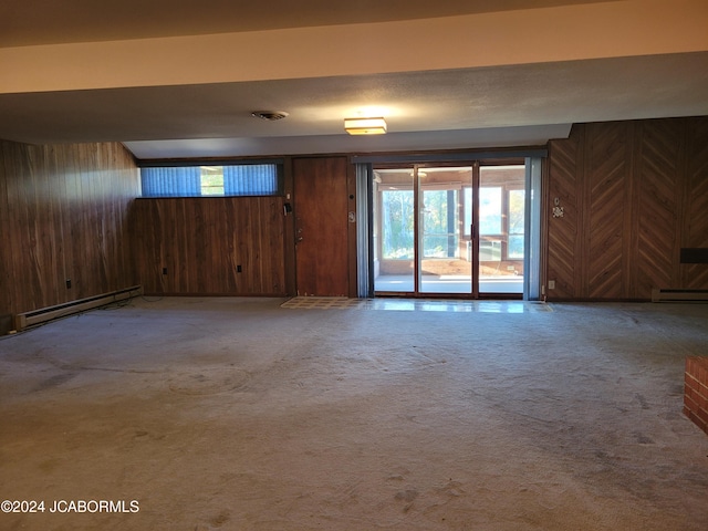 unfurnished room featuring carpet flooring, wood walls, and a baseboard heating unit