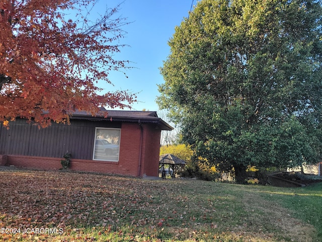 view of side of home with a gazebo and a lawn