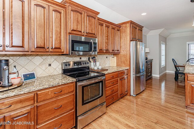 6002 Sterling Ridge Rd, Jefferson City, MO 65101 - kitchen featuring stainless steel appliances, brown cabinets, light wood-style floors, light stone counters, and recessed lighting