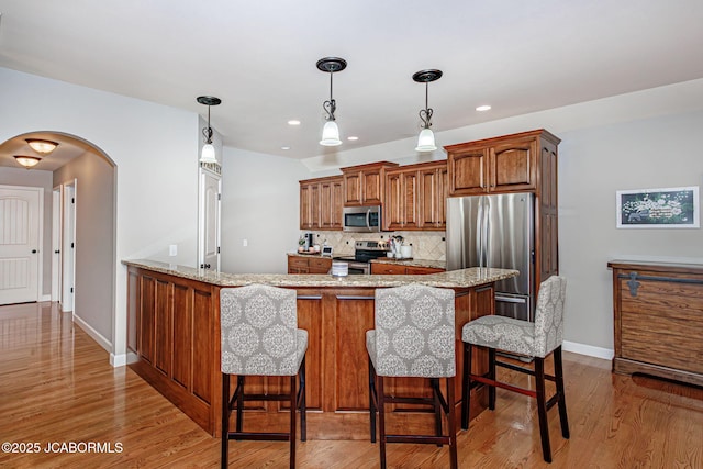 6002 Sterling Ridge Rd, Jefferson City, MO 65101 - kitchen featuring stainless steel appliances, arched walkways, a peninsula, a kitchen breakfast bar, and recessed lighting