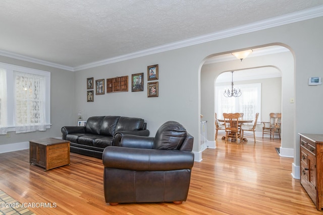 1311 Elmerine Ave, Jefferson City, MO 65101 - living room with arched walkways, light wood finished floors, crown molding, a chandelier, and a textured ceiling