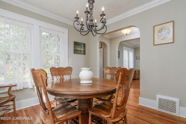 1311 Elmerine Ave, Jefferson City, MO 65101 - dining area featuring arched walkways, light wood-type flooring, ornamental molding, a textured ceiling, and a chandelier
