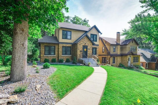 1311 Elmerine Ave, Jefferson City, MO 65101 - tudor home featuring stucco siding, a chimney, a front lawn, and a shingled roof