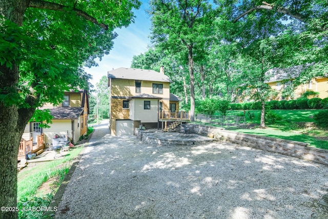 1311 Elmerine Ave, Jefferson City, MO 65101 - back of property featuring a chimney, a deck, a garage, and driveway