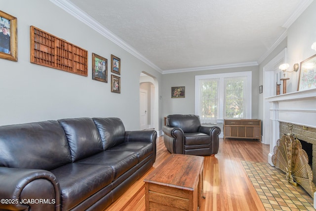 1311 Elmerine Ave, Jefferson City, MO 65101 - living area featuring wood finished floors, arched walkways, ornamental molding, a fireplace with flush hearth, and a textured ceiling