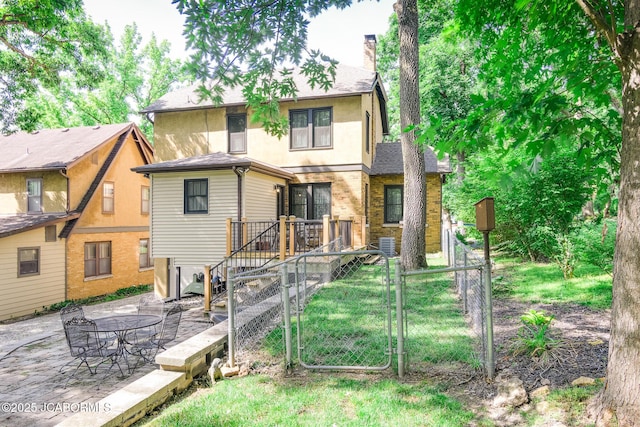 1311 Elmerine Ave, Jefferson City, MO 65101 - back of house with a chimney, a gate, a patio area, stucco siding, and roof with shingles