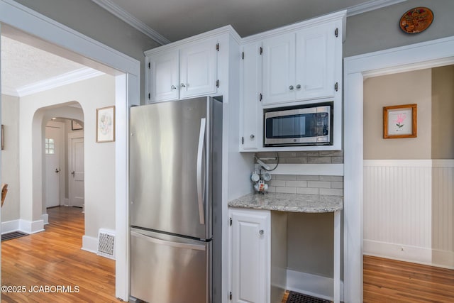 1311 Elmerine Ave, Jefferson City, MO 65101 - kitchen with appliances with stainless steel finishes, light wood finished floors, arched walkways, crown molding, and light stone counters