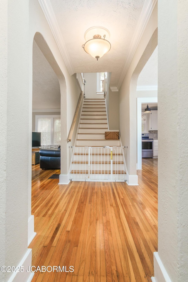 1311 Elmerine Ave, Jefferson City, MO 65101 - stairs with ornamental molding, hardwood / wood-style floors, arched walkways, a textured ceiling, and a textured wall