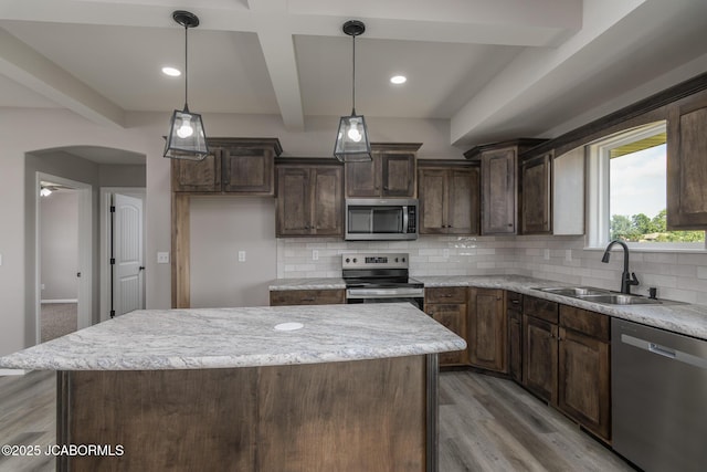 5705 Summerfield Ct, Jefferson City, MO 65109 - kitchen featuring appliances with stainless steel finishes, beam ceiling, decorative backsplash, light wood finished floors, and a center island