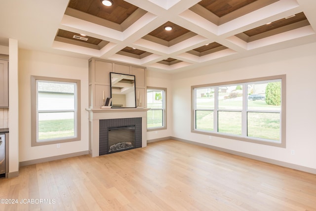 unfurnished living room featuring beam ceiling, light hardwood / wood-style flooring, coffered ceiling, and a brick fireplace