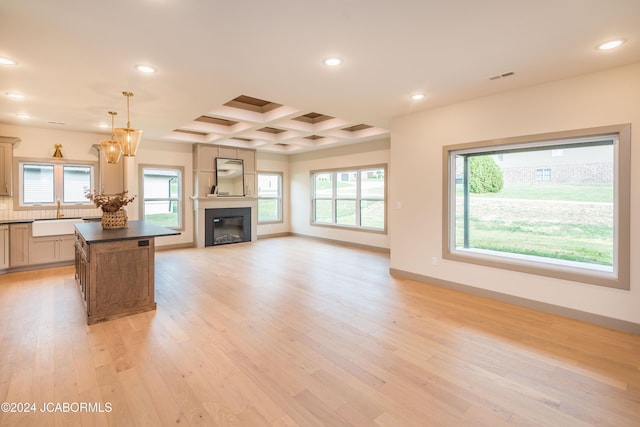 unfurnished living room featuring beamed ceiling, light wood-type flooring, sink, and coffered ceiling