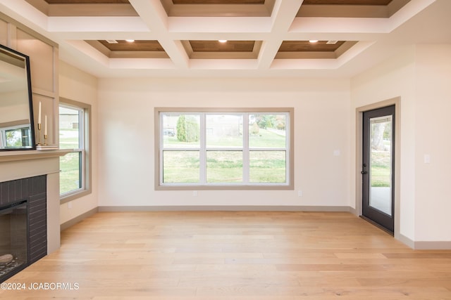 unfurnished living room featuring coffered ceiling, beam ceiling, light wood-type flooring, and a brick fireplace