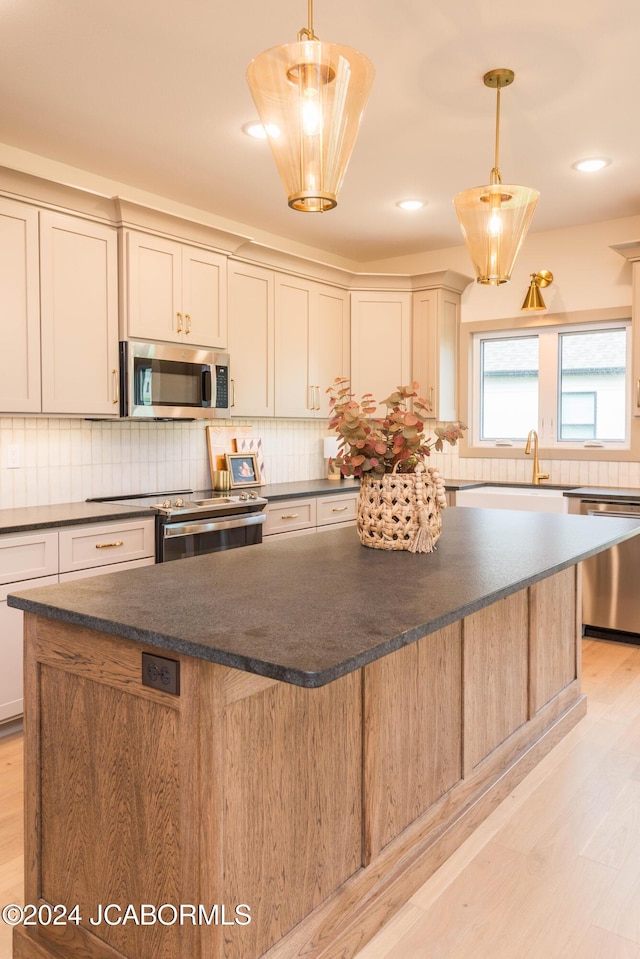 5607 Birch Creek Ln, Jefferson City, MO 65101 - kitchen with appliances with stainless steel finishes, a kitchen island, decorative backsplash, light wood-type flooring, and recessed lighting