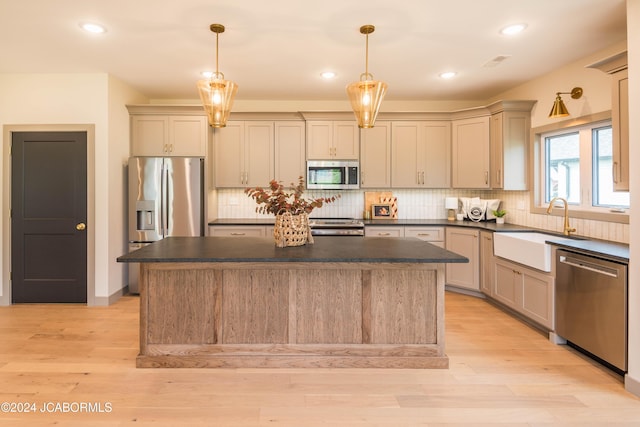 kitchen featuring hanging light fixtures, a kitchen island, stainless steel appliances, and light hardwood / wood-style floors