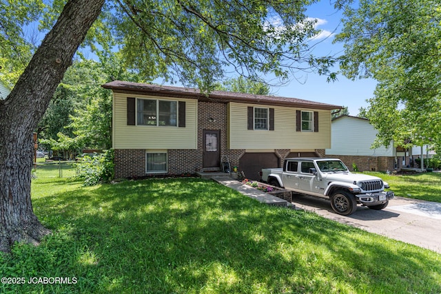 5501 S Brooks Dr, Jefferson City, MO 65109 - split foyer home featuring concrete driveway, brick siding, an attached garage, a front yard, and entry steps