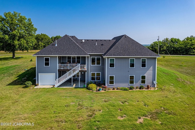 rear view of property with a lawn, an attached garage, stairs, and a shingled roof