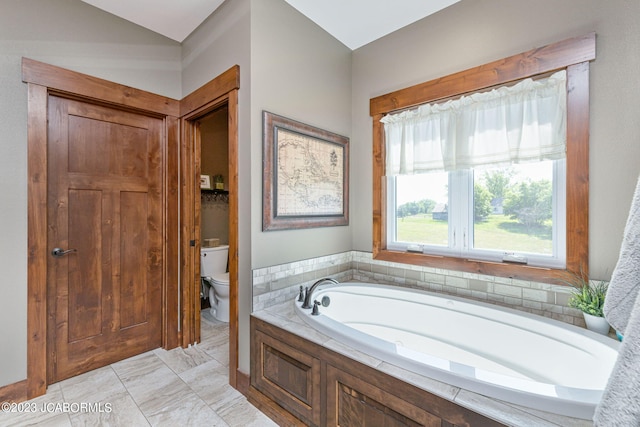 bathroom featuring a garden tub and toilet