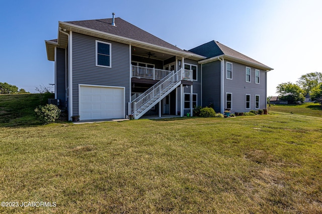 rear view of property featuring a yard, stairway, an attached garage, and a ceiling fan