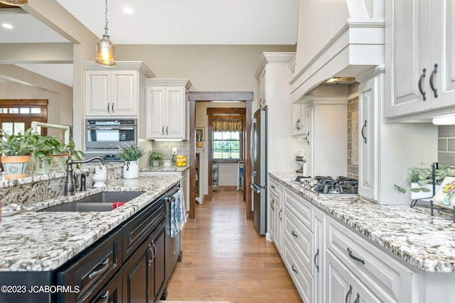 kitchen featuring light wood-style flooring, a sink, white cabinetry, appliances with stainless steel finishes, and decorative backsplash