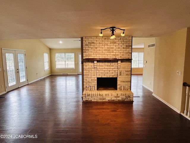 unfurnished living room featuring a fireplace, a wealth of natural light, and dark wood-type flooring