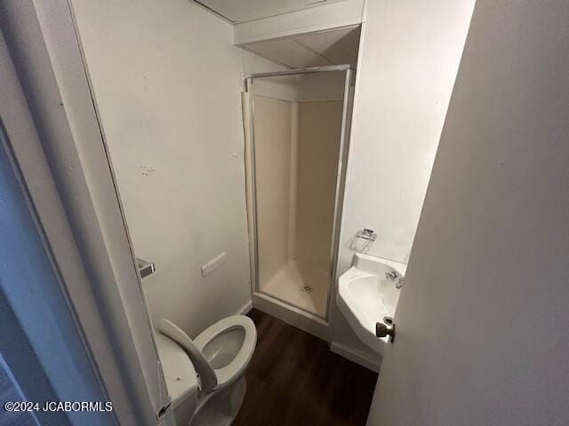 bathroom with wood-type flooring, toilet, a shower with shower door, and sink