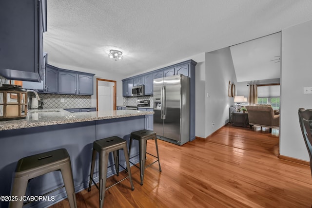 990 Diamond Rdg, Jefferson City, MO 65109 - kitchen featuring appliances with stainless steel finishes, a sink, light wood finished floors, a peninsula, and tasteful backsplash