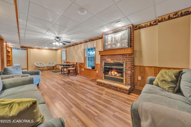 990 Diamond Rdg, Jefferson City, MO 65109 - living room featuring a fireplace, wainscoting, wood walls, wood finished floors, and a drop ceiling