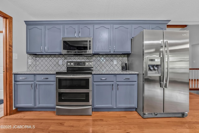 990 Diamond Rdg, Jefferson City, MO 65109 - kitchen featuring stone counters, decorative backsplash, stainless steel appliances, and light wood-style flooring