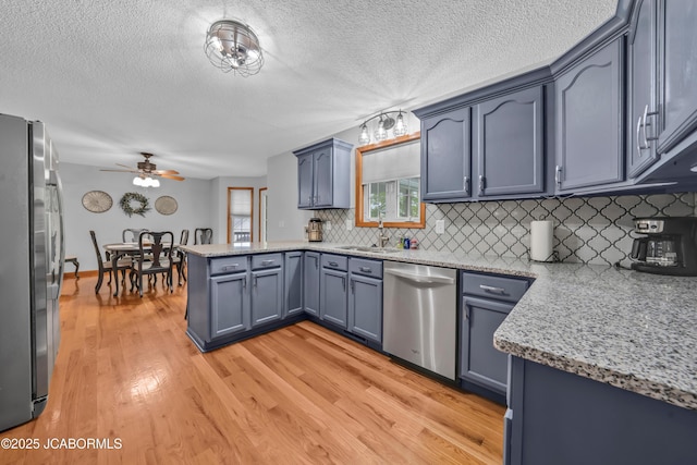 990 Diamond Rdg, Jefferson City, MO 65109 - kitchen with a peninsula, light wood-style floors, tasteful backsplash, a ceiling fan, and stainless steel appliances