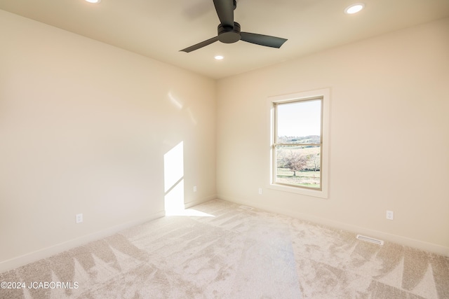 spare room with ceiling fan and light colored carpet