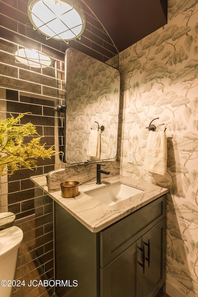 bathroom with vanity, toilet, and lofted ceiling