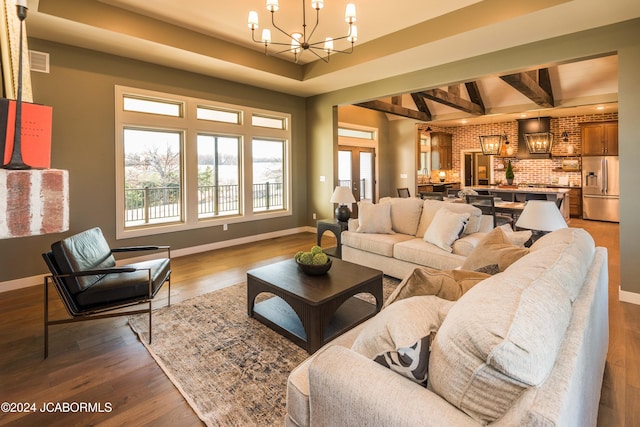 living room featuring hardwood / wood-style flooring, beam ceiling, brick wall, and a chandelier