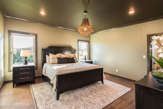 bedroom featuring light hardwood / wood-style flooring, multiple windows, and ornamental molding