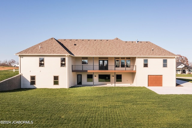 rear view of property featuring a patio, a yard, a balcony, and a garage