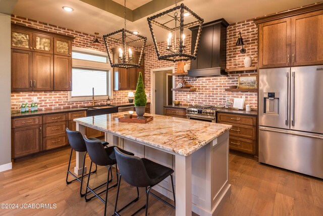 kitchen featuring appliances with stainless steel finishes, brick wall, pendant lighting, dark stone countertops, and a kitchen island