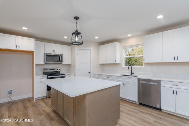 kitchen with a kitchen island, white cabinetry, sink, and appliances with stainless steel finishes