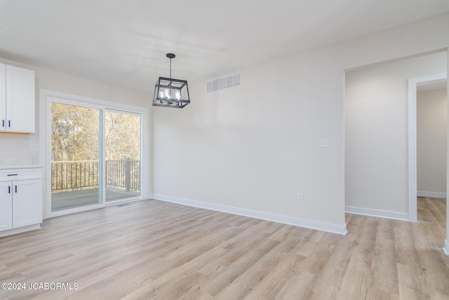 unfurnished dining area featuring a chandelier and light wood-type flooring