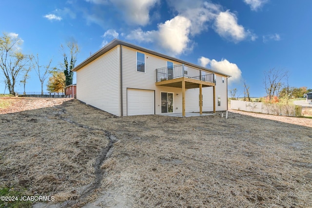 rear view of house featuring a balcony and a garage