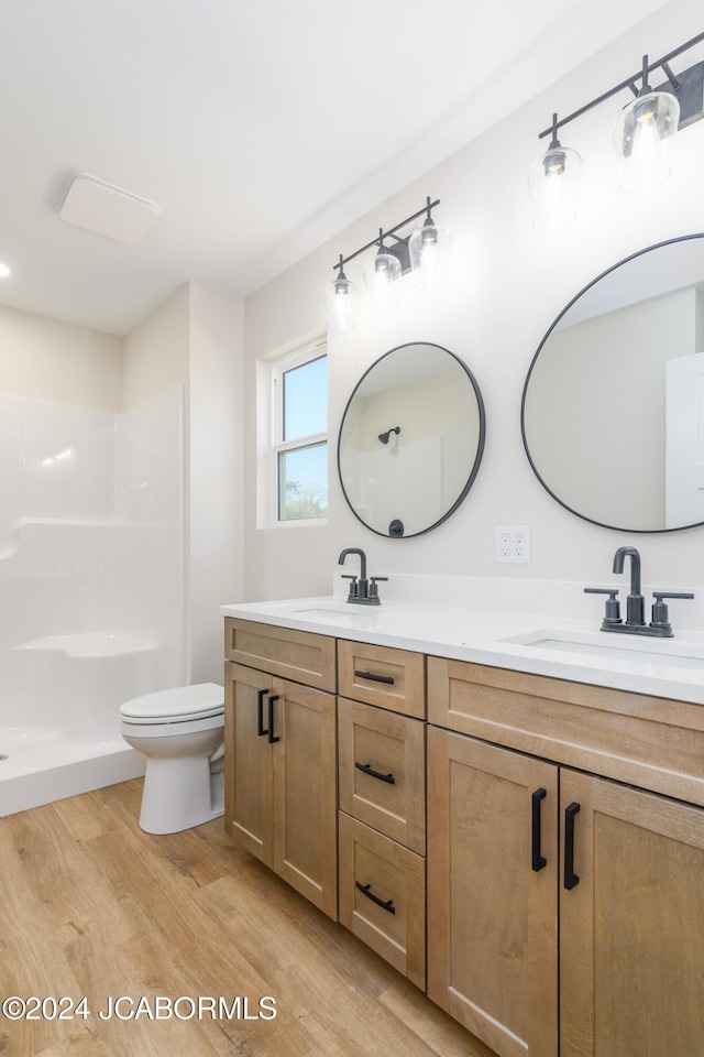 bathroom featuring hardwood / wood-style flooring, vanity, toilet, and a shower