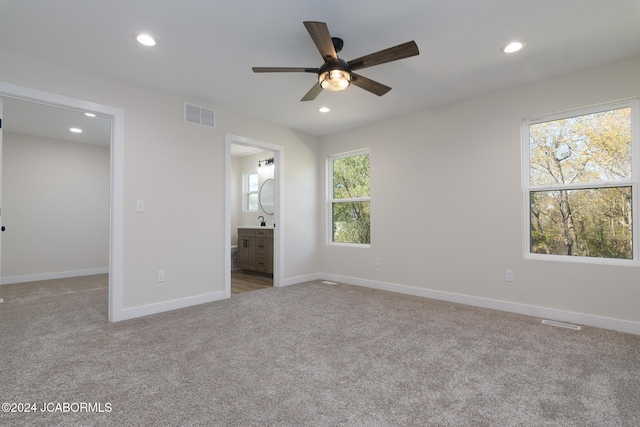 unfurnished bedroom featuring ensuite bathroom, ceiling fan, light colored carpet, and sink