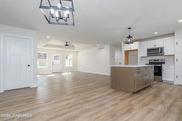 kitchen featuring white cabinets, appliances with stainless steel finishes, a center island, and decorative light fixtures