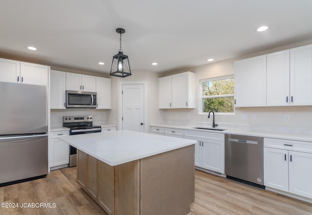 kitchen featuring white cabinets, a kitchen island, sink, and appliances with stainless steel finishes