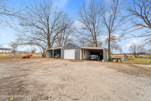 view of outbuilding with a carport, a garage, and a playground