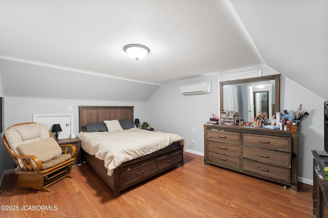 bedroom featuring hardwood / wood-style flooring, lofted ceiling, and an AC wall unit