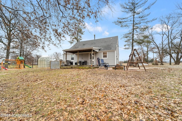 back of house with a playground and an outbuilding