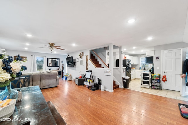 living room with ceiling fan, sink, and light hardwood / wood-style floors