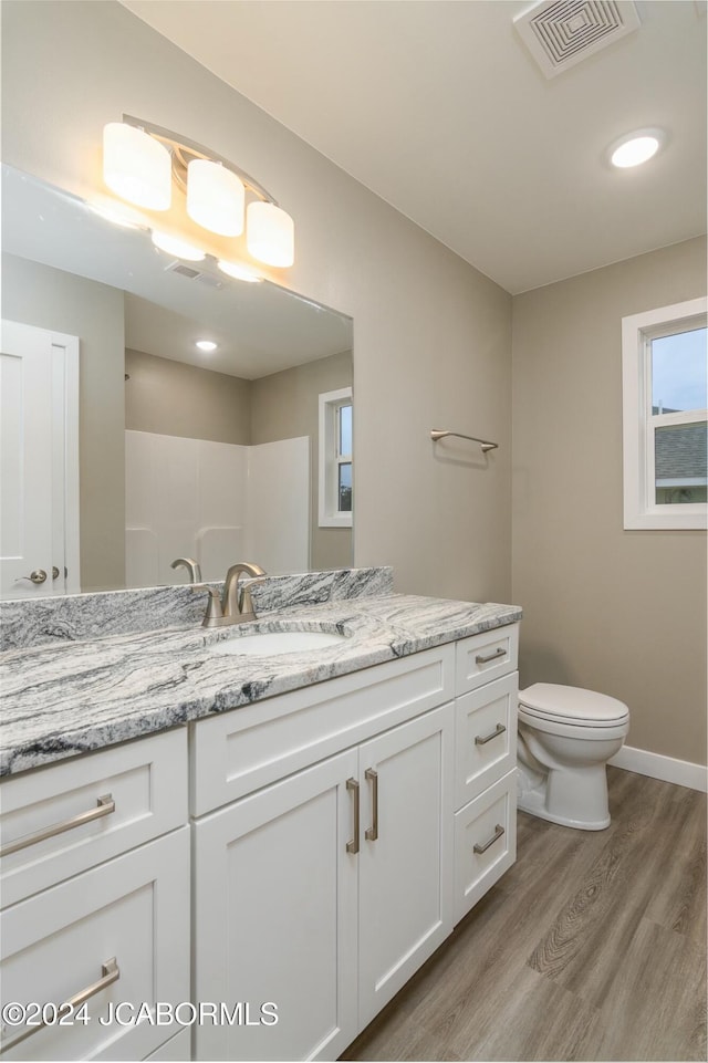 bathroom with toilet, vanity, wood-type flooring, and walk in shower